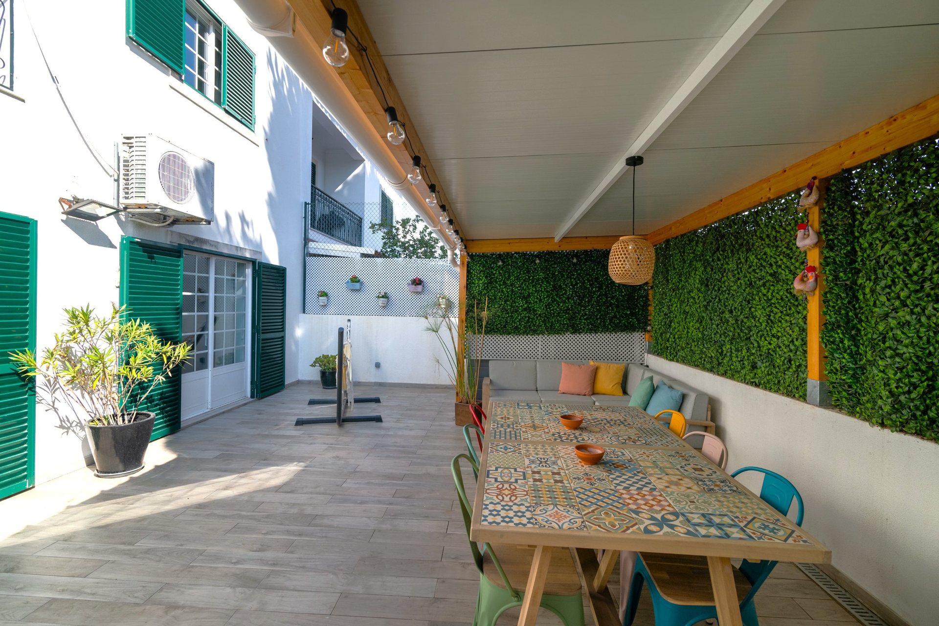 Logradouro coberto com mesa de azulejos e parede verde
